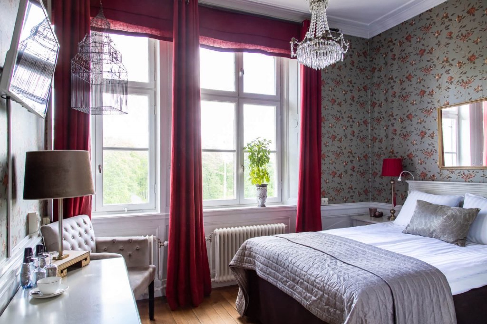 Hotellrum med kristallkrona och röda gardiner